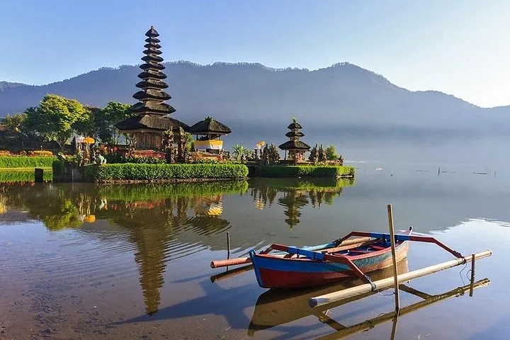 Tempelanlage Pura Ulun Danu Bratan an einem See mit einem Holzboot.